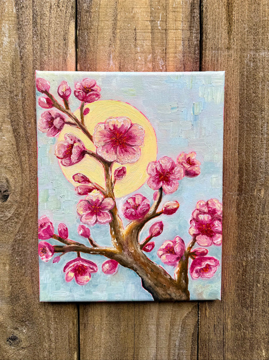 Painting of a cherry blossom branch with pink flowers on a wooden background