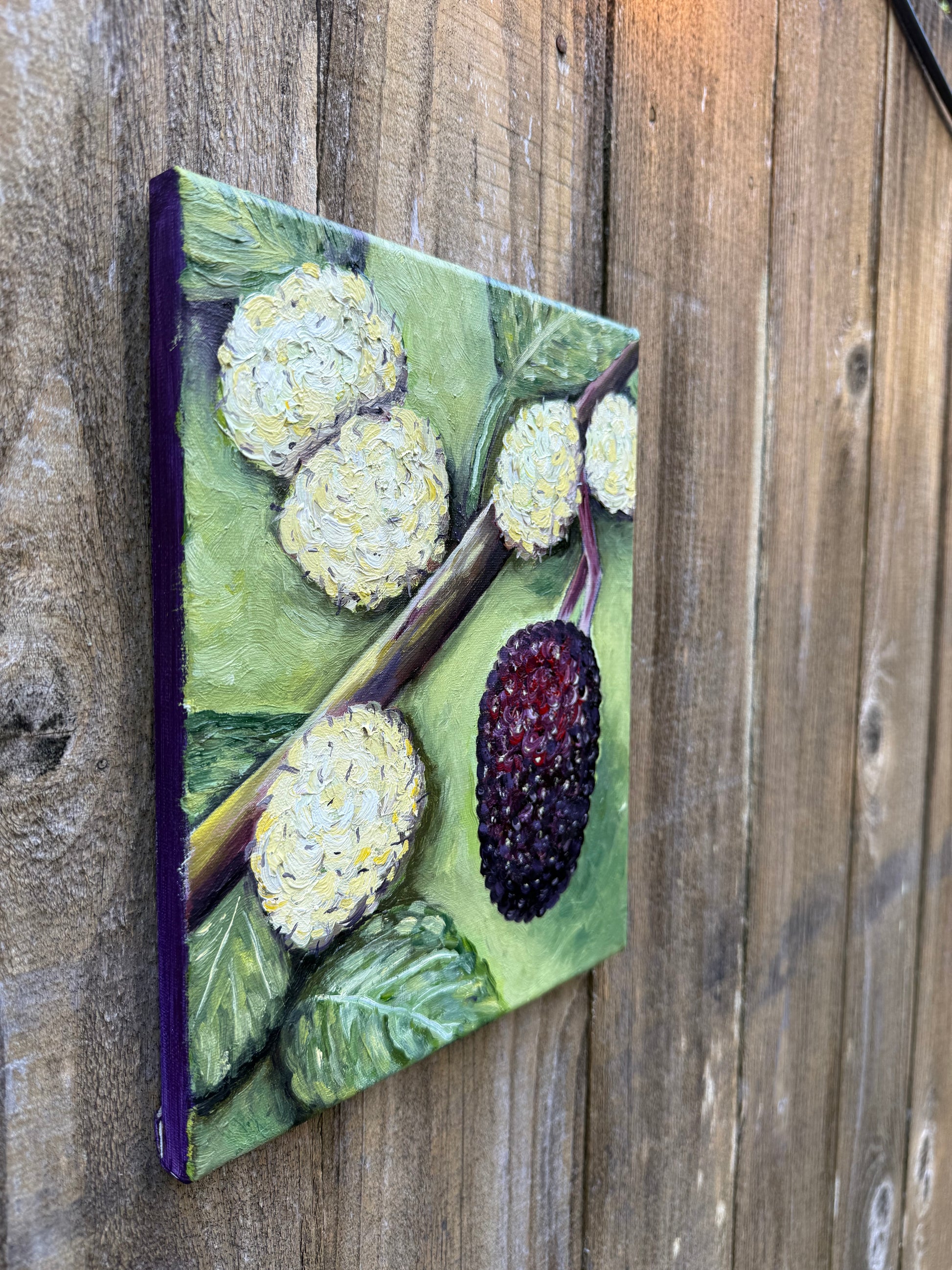 oil painting with mulberries growing that look like blackberries and white flowers on a wooden surface
