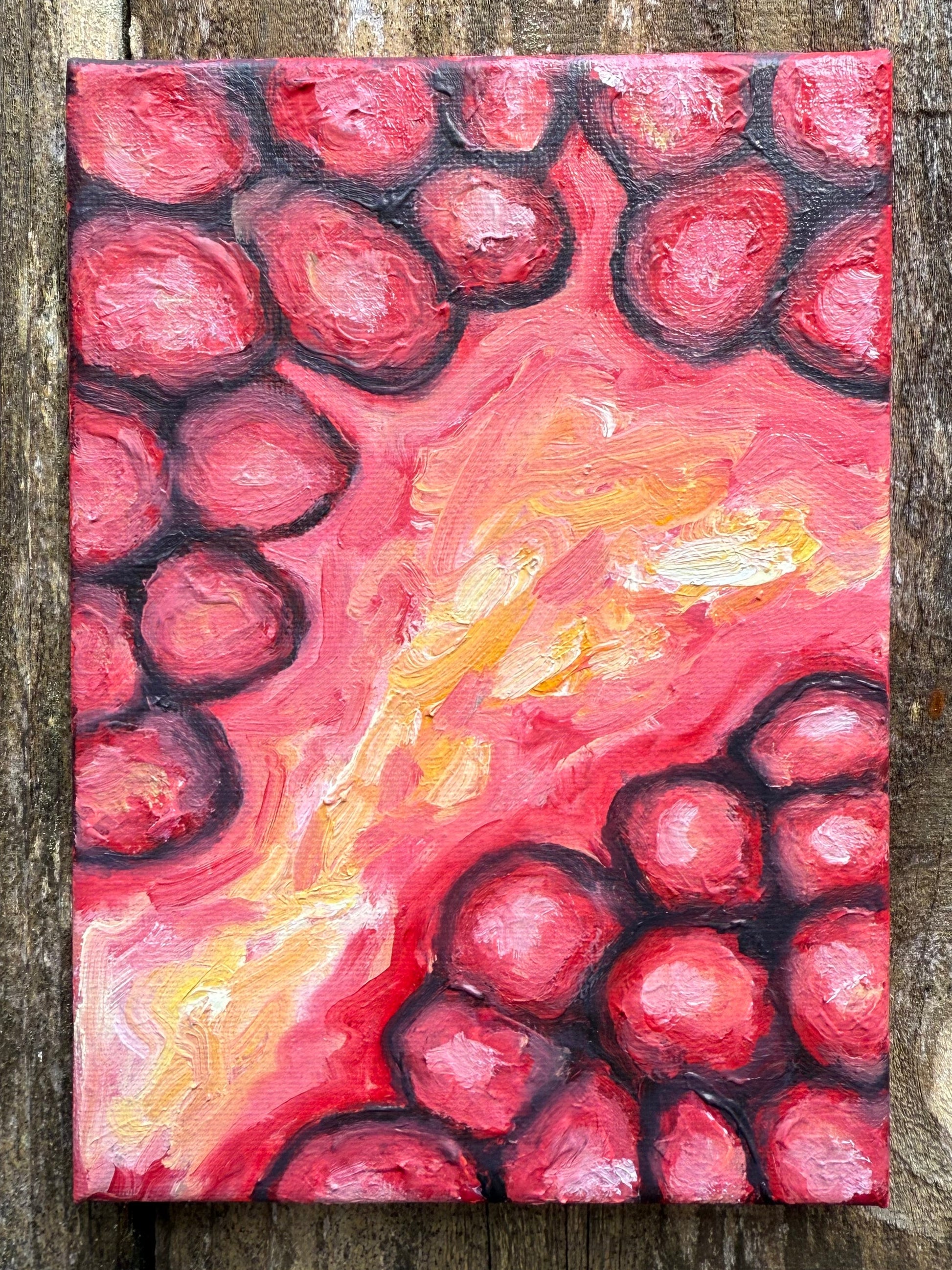 Abstract painting with of a pomegranate pink and red hues on a wooden surface