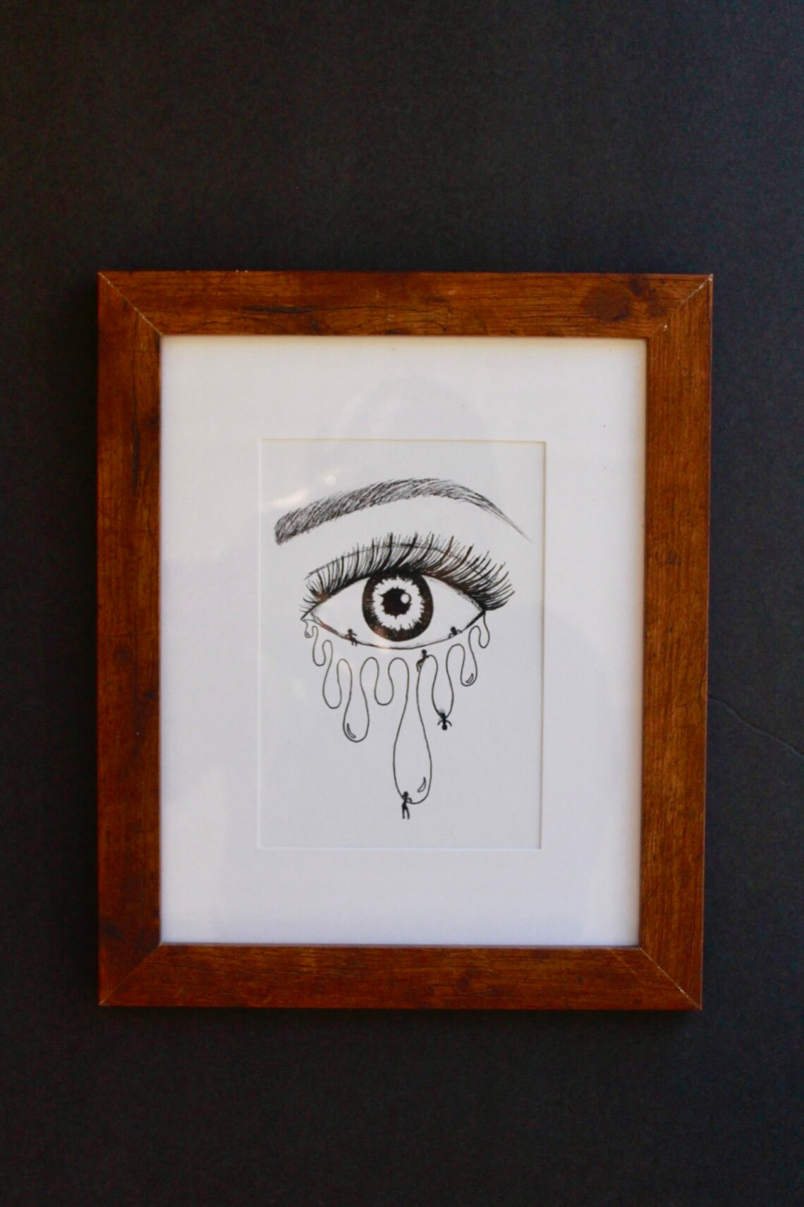 original black ink drawing of an eye that is melting with multiple stick figured hanging from the eye